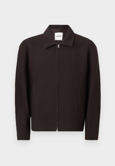 Σκούρο καφέ μπουφάν με φερμουάρ και γιακά, δύο μπροστινές τσέπες και μακριά μανίκια, με ετικέτα Sandro μέσα στον γιακά.