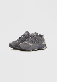 Pair of gray New Balance athletic sneakers with mesh and suede overlays, black and beige accents, and chunky soles on white background.