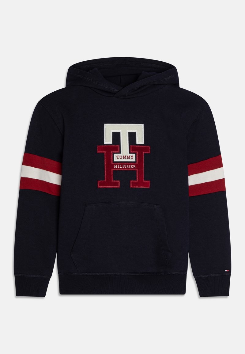 Sweat à capuche bleu marine avec poche kangourou devant, bandes rouges et blanches sur les manches, et grand logo "TH Tommy Hilfiger" rouge et blanc sur la poitrine.