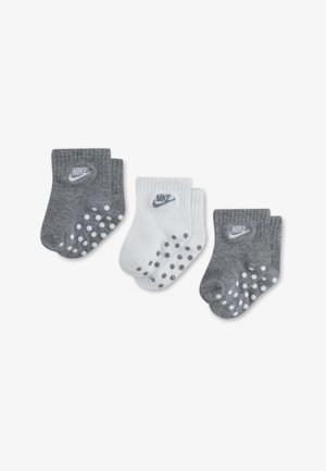 Pilkos ir baltos Nike kojinės, su gumbuotais kraštais ir neslystančiais taškais ant padų. Kiekviena pora turi logotipą šone. Iš viso trys poros.