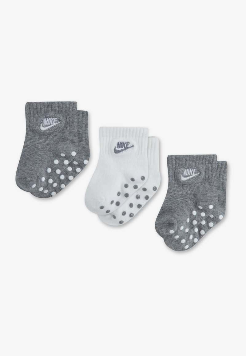 Calcetines Nike grises y blancos, con puños acanalados y puntos antideslizantes en las suelas. Cada par tiene un logo en el lateral. Un total de tres pares.