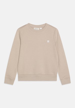 Felpa beige realizzata in tessuto morbido, presenta un collo rotondo, maniche lunghe, polsini e orlo a coste, e una piccola patch con logo sul petto.