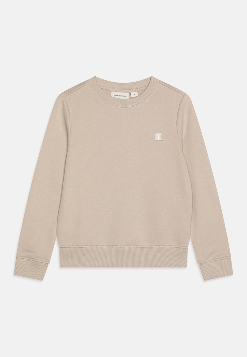 Sudadera beige hecha de tela suave, con cuello redondo, mangas largas, puños y dobladillo acanalados, y un pequeño parche con el logo en el pecho.