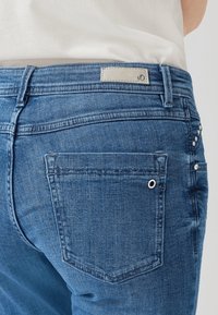 Jeans de mezclilla azul con corte recto, que cuentan con un bolsillo trasero y adornados con pequeñas strass a lo largo de la costura. Etiqueta en la cinturilla.