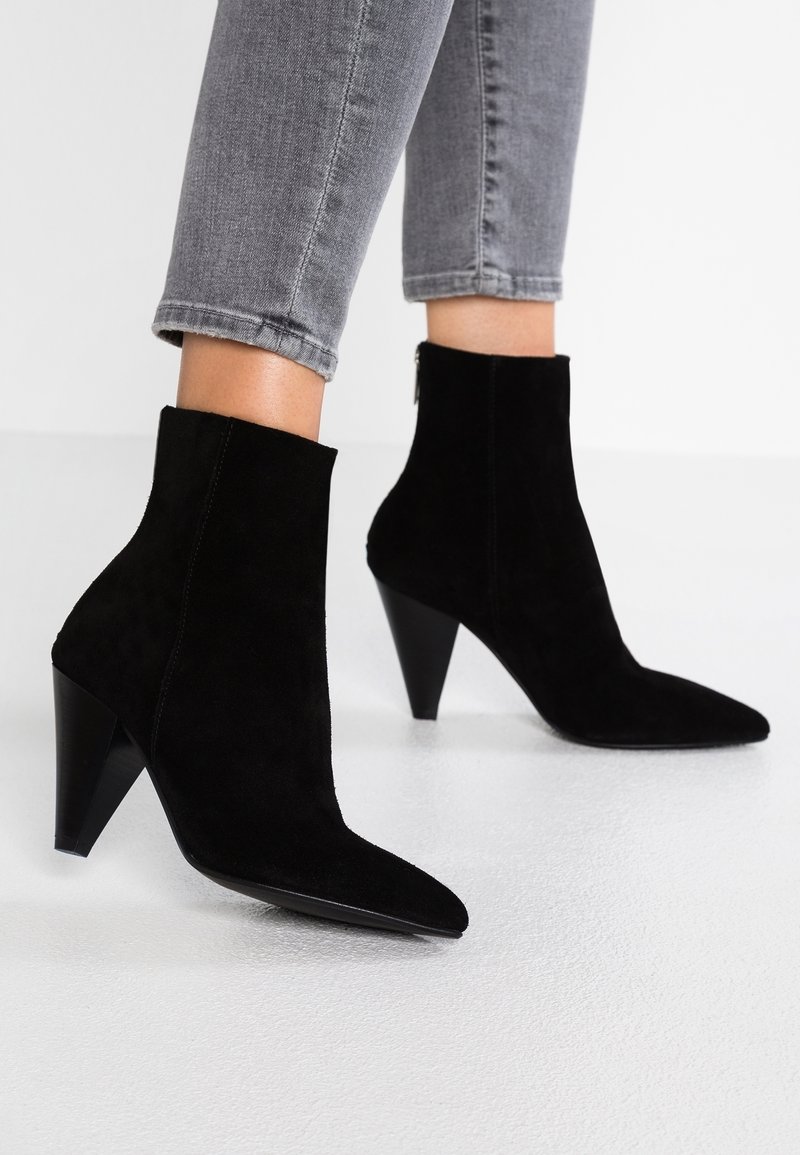 Czarne zamszowe botki za kostkę z ostro zakończonym noskiem i stożkowym obcasem, o gładkiej fakturze i detalem zamka z tyłu.