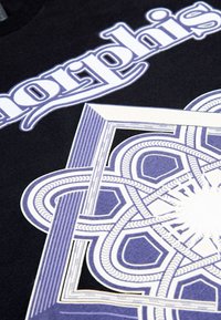 Černé tričko má velký bílý a purpurový grafický design s propracovanými geometrickými vzory a slovo "morphis" v stylizovaném písmu.