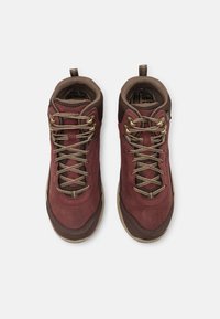 Rote und braune Wanderschuhe mit einer strukturierten Oberseite, Metallösen für die Schnürsenkel und einer Gummisohle. Verfügt über einen Ziehgriff an der Ferse für einfaches Anziehen.