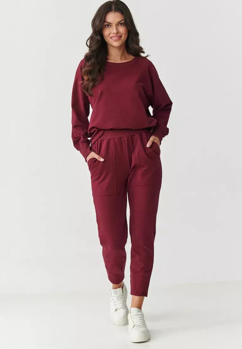Burgundowy zestaw bluzy i joggerów wykonany z miękkiego materiału. Joggerzy mają boczne kieszenie i zwężany krój mankietów, zestawione z białymi trampkami.