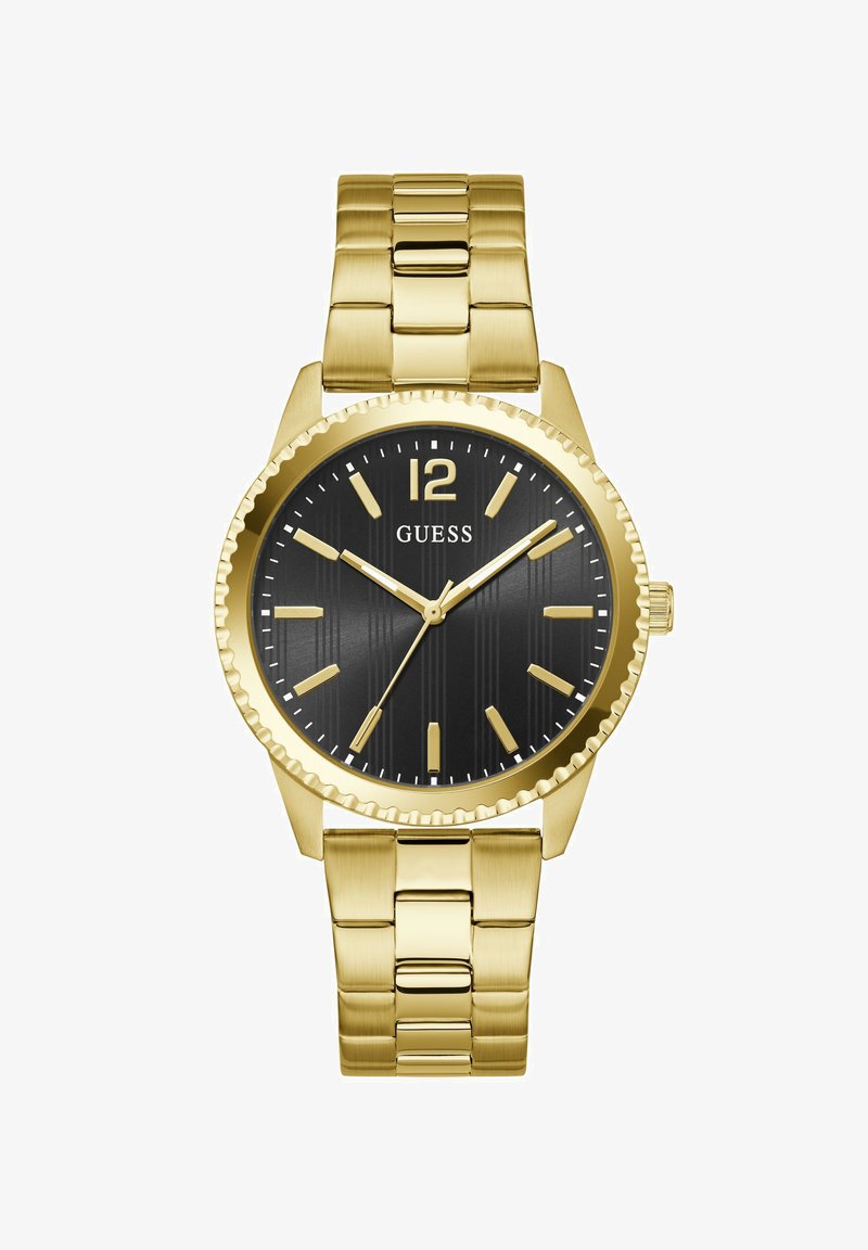 Ρολόι βραχιόλι από χρυσό μέταλλο με μαύρο καντράν, χρυσούς δείκτες ώρας και το όνομα της μάρκας "GUESS" κάτω από τη θέση 12 η ώρα.