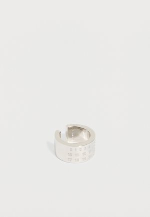 Širok srebrn odprt prstan z vgraviranimi številkami, razporejenimi v vrstah od 0 do 30 na preprostem belem ozadju.