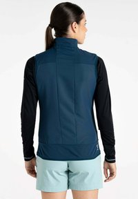 Marineblaue ärmellose Weste mit hohem Kragen, aus glattem Stoff gefertigt, kombiniert mit einem schwarzen Langarmoberteil und hellblauen Shorts.