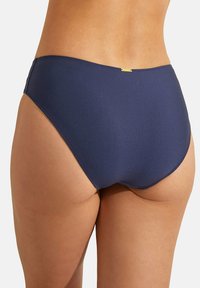 Culotte de bikini bleu marine avec un style taille haute, texture lisse et une petite étiquette dorée à l'arrière.