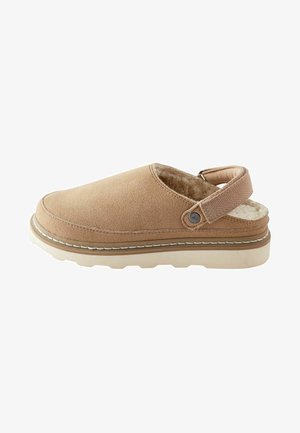 Saboți din suede de culoare maro deschis, cu căptușeală interioară moale, curea pe spate, cusături albe și o talpă texturată pentru aderență și confort.