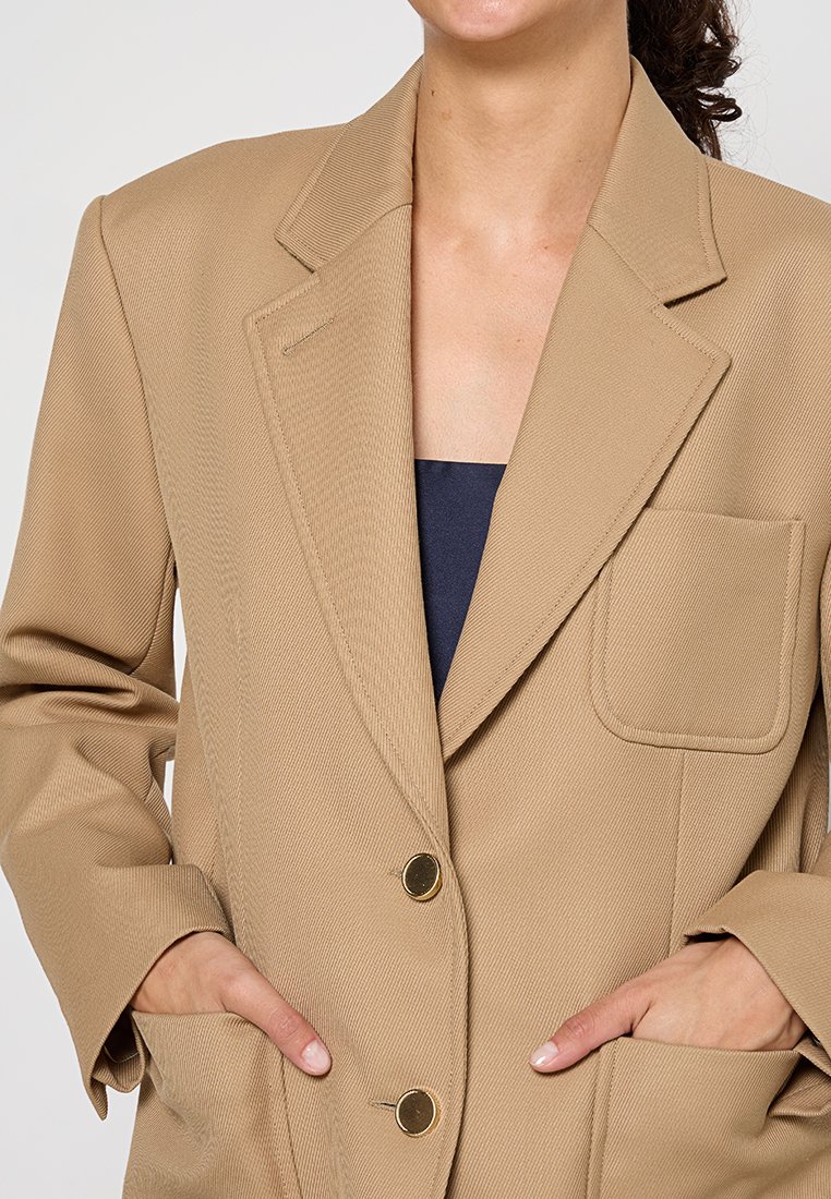 Beige blazer met grote revers, twee knopen aan de voorkant, een borstzak en textiel met structuur. Vo pockets met open kleppen, ontspannen fit.