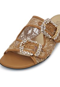 Infradito color nocciola con dettagli in pizzo intricati, doppie fibbie decorate con cristalli e una suola piatta liscia.