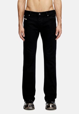 Mustar mustad denim püksid sirge lõikega, viie taskuga disain, hõbedane riistvara ja peen brändingu detail esimeses taskus.