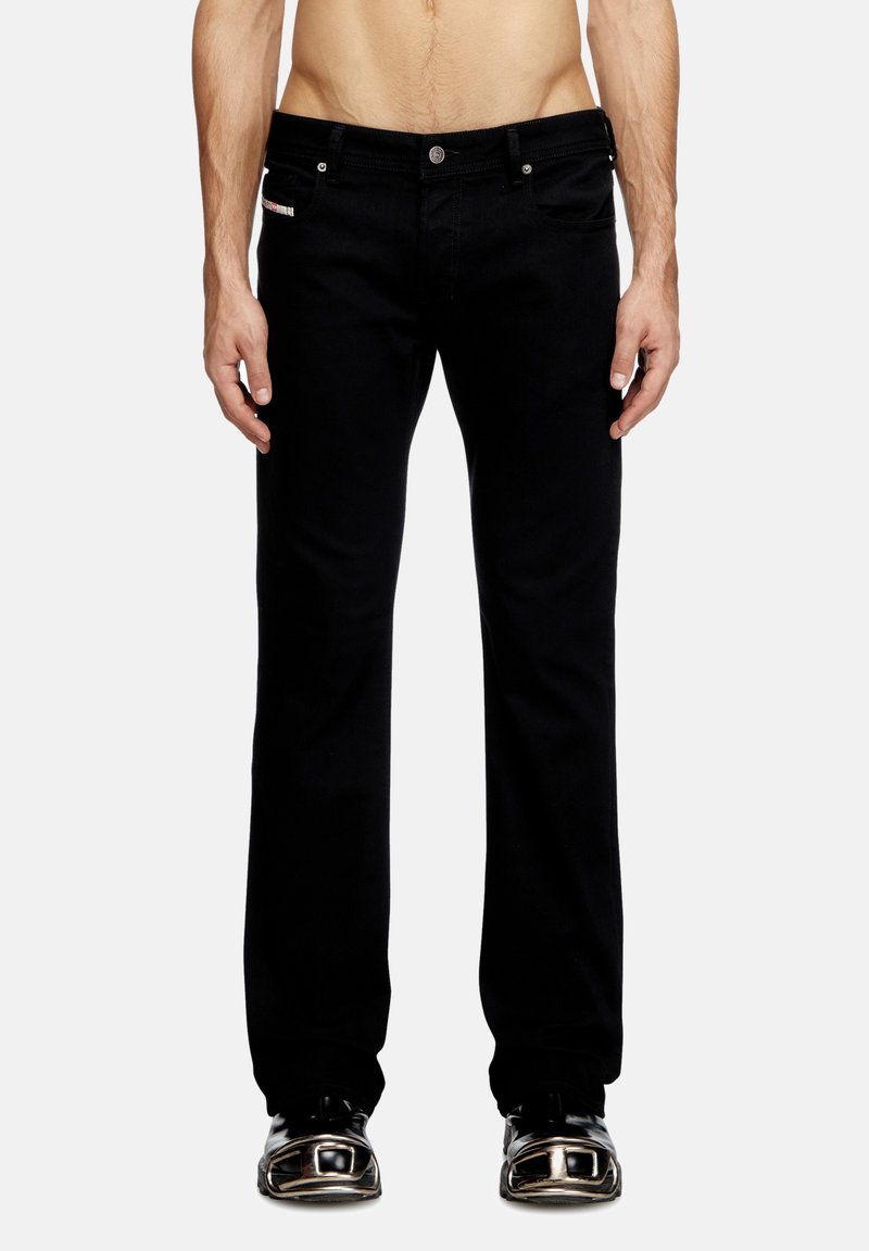 Jeans de mezclilla negra con un corte recto, diseño de cinco bolsillos, herrajes plateados y un sutil detalle de marca en el bolsillo delantero.