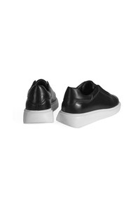 Zwarte leren sneakers met een gladde textuur, afgeronde vorm en contrasterende witte rubberen zolen. Kenmerken een minimalistisch ontwerp en instapstijl.