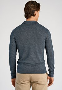 Granatowy dzianinowy sweter z kołnierzem polo, długimi rękawami i ściągaczem u dołu. Gładka faktura, dopasowany krój z subtelnym wzorem.