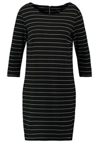 Svart klänning med vita horisontella ränder, långa ärmar, rund halsringning och en dragkedja bak. Slät tyg, åtsittande silhuett.