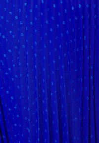 Blå plisserad tyg med ett subtilt prickmönster. Texturen är genomskinlig och lätt, med varierande nyanser av blått.