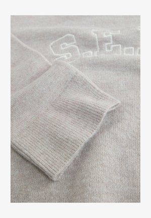 Grauer Strickpullover-Stoff mit gerippten Bündchen. Hat eine strukturierte Oberfläche und gestickte weiße Schriftzüge auf der Vorderseite. Weich und gemütlich im Aussehen.