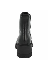 Botas de tobillo de cuero negro con una superficie texturizada, un cierre de cremallera en la parte trasera, puntera redonda y suela de goma negra gruesa.