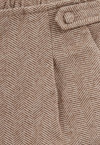 Brūnas herringbone raksta audums ar mīkstu tekstūru, kuram ir savilkta josta un izsmalcināta loku akcents.