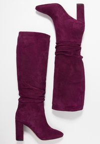 Botas altas de ante púrpura con un ajuste ceñido, que presentan una punta afilada y un tacón grueso y cuadrado para estabilidad y estilo.