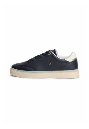 Lage marineblauwe sneaker met witte gevoerde kraag, crèmekleurige rubberen zool, zwarte veters en klein gouden logo op het zijpaneel.