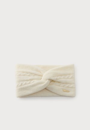 Bandeau en tissu doux couleur crème avec un détail de nœud torsadé et un petit logo Hugo doré sur un côté.