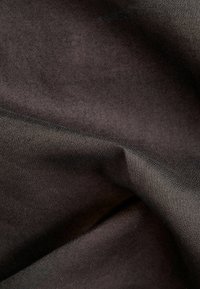 Tissu gris foncé avec des plis doux et une surface légèrement texturée sous un éclairage doux.