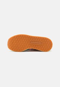 Adidas sneaker sole featuring an orange rubber bottom with a textured diamond pattern, embossed logo, and rounded edges.
