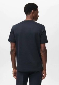 Camiseta negra de manga corta hecha de algodón, con un cuello redondo y un corte recto. Textura suave sin patrones ni acentos visibles.