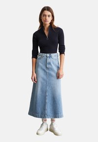 Marineblaue, gerippte Zip-Up-Bluse kombiniert mit einem hellblauen Jeans-Maxirock. Verfügt über eine taillierte Silhouette, schlichte Nähten und weiße Sneaker mit Akzenten.