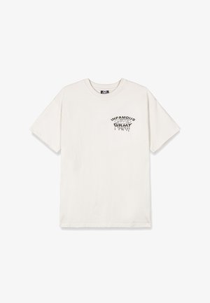 Kremowy t-shirt z bawełny z czarnym graficznym napisem "INFAMOUS" z efektem kapania, luźny krój i krótkie rękawy.