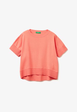 Pull en maille corail à manches courtes avec col rond, poignets et ourlet côtelés, avec un dos légèrement plus long et une étiquette de marque verte à l’intérieur du col.