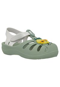 Sandalini verde con suola spessa, design a intagli, cinturino bianco regolabile e decorazione di un personaggio dei cartoni animati giallo sul davanti.