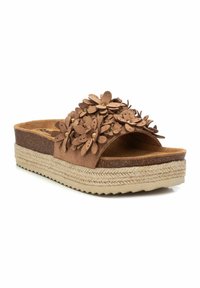 Sandal con tiras de ante marrón que presenta una aplicación floral en la correa, plantilla de corcho y suela de yute envuelta al estilo espadrille.