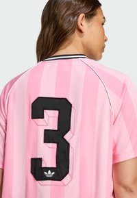 Pink sports jersey featuring vertical stripes, a large black "3" stitched on the back, and a small white logo at the hem.