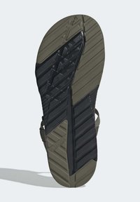 Ute sandal såle med et teksturert gummidesign med riller, farget hovedsakelig i svart med oliven grønn aksenter.