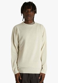 Maglione color crema realizzato in tessuto morbido, con collo rotondo, maniche lunghe e polsini e bordo a coste. Texture liscia, vestibilità comoda.