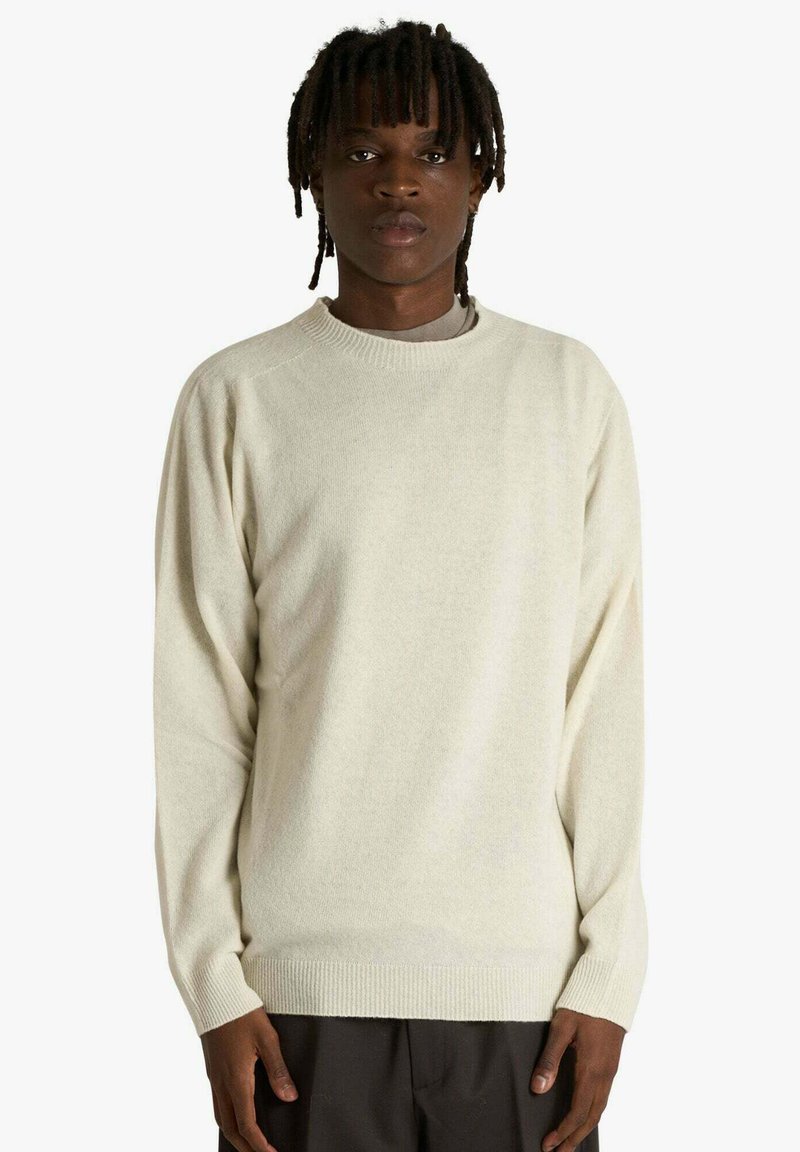 Maglione color crema realizzato in tessuto morbido, con collo rotondo, maniche lunghe e polsini e bordo a coste. Texture liscia, vestibilità comoda.