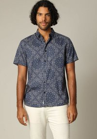 Marineblauwe kortemouwen shirt met bloemenpatronen, een knoopsluiting kraag en een gladde stoftextuur, gecombineerd met lichtgekleurde broek.