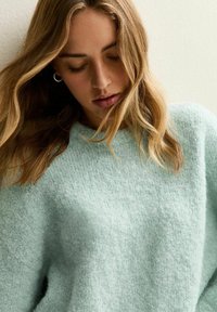 Ljusblå, strukturerad stickad tröja med avslappnad passform och rundad nacke. Mjuk material med en fluffig yta och sänka axlar.