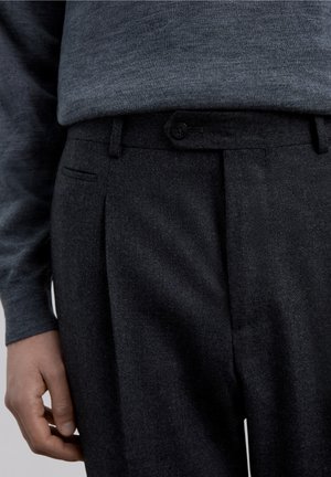Pantalones de lana en gris oscuro con corte recto, con frente plano, cierre de un solo botón y bolsillos laterales. Tejido texturizado.