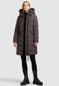 Puffervest i mørkegrå, med hætte, lynlåslukning og sidelommer. Stoffet er quiltet med en glat tekstur og en afslappet pasform.