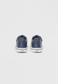 Sötétkék bőrsneaker fehér gumitalppal, párnázott boka- és nyelvrésszel, márkás sarokkialakítással és fűzős záródással.