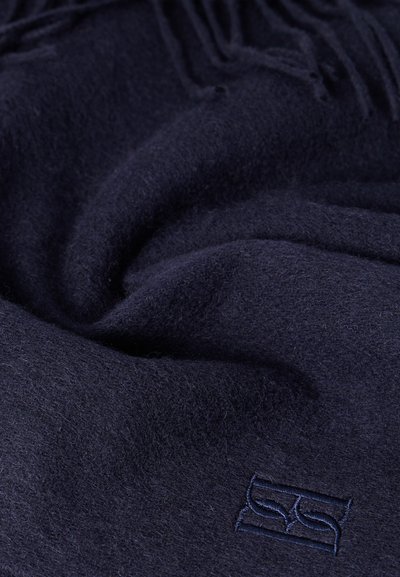 Μάλλινο κασκόλ σε σκούρο ναυτικό μπλε, με μαλακή υφή, κρόσσια στις άκρες και κεντημένο λογότυπο στη κάτω γωνία.