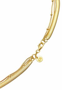 Collier superposé en ton doré avec des chaînes texturées, un fermoir en forme de homard et une étiquette circulaire avec une inscription gravée.